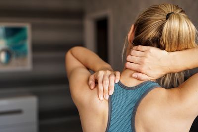 Crampe musculaire Une femme en haut de sport se frotte la nuque, qui semble douloureuse