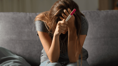 A woman holds a pregnancy test and despairs