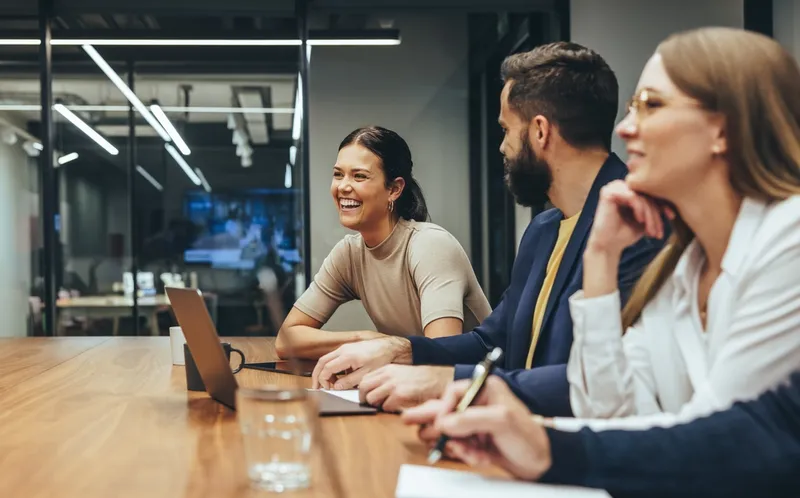 female worker smiles in meeting with male and female colleagues