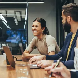 female worker smiles in meeting with male and female colleagues
