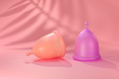 orange and purple menstrual cups on pink background