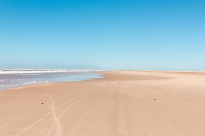 A stretch of Praia do Cassino on a clear blue sky day.