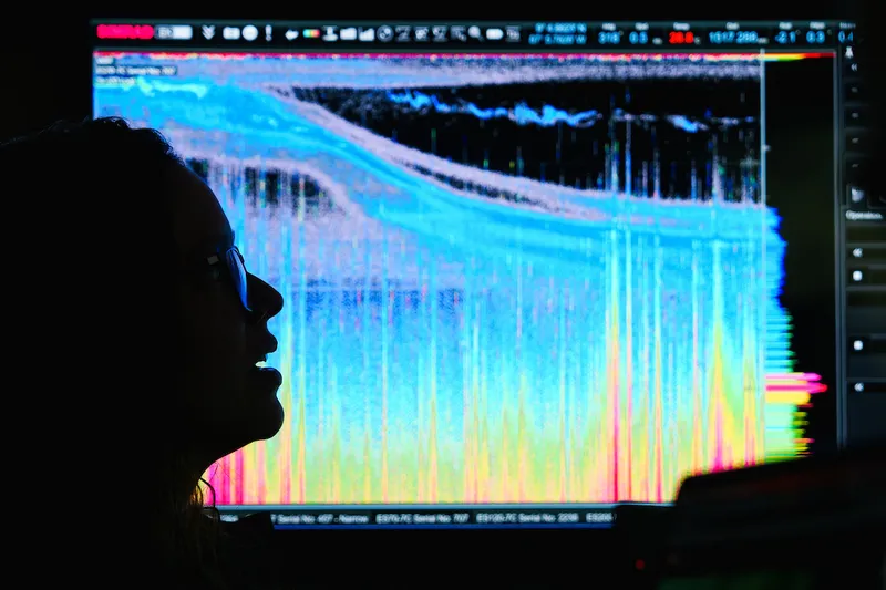 Beatriz Naranjo (Scientist, Universidad de Costa Rica) is silhouetted against colorful data displayed on the screen onboard the research vessel Falkor (too)