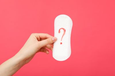 Hand holding sanitary pad with red question mark on it