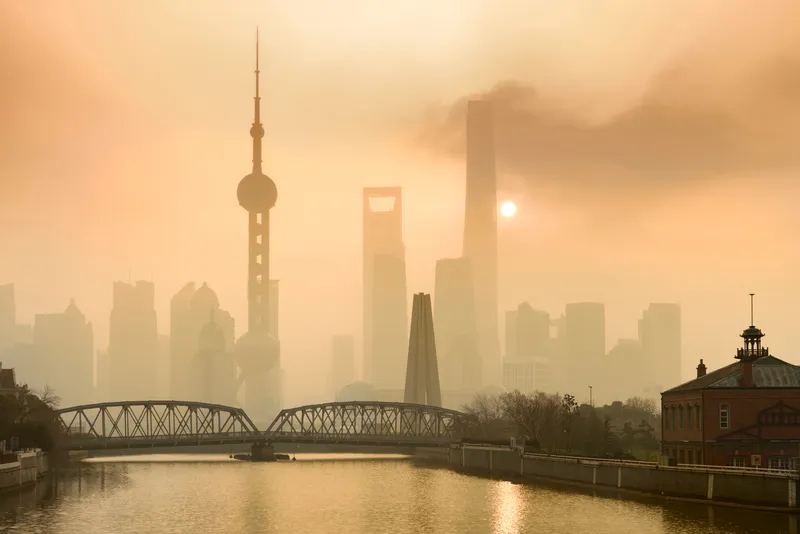 View of Shanghai skyline with orange sky; the skyscrapers are partially obscured from view due to the haze in the air from the pollution