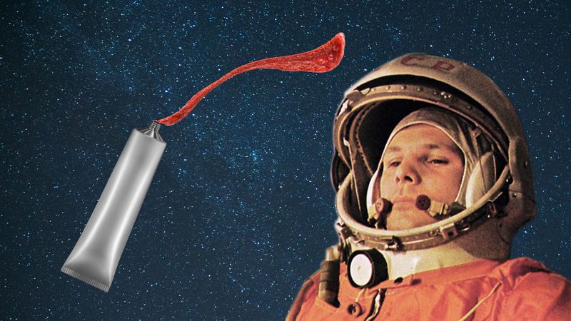 An image of yuri gagarin in his space suit over a starry background. A non-descriptive tube of paste is squirting a paste around him