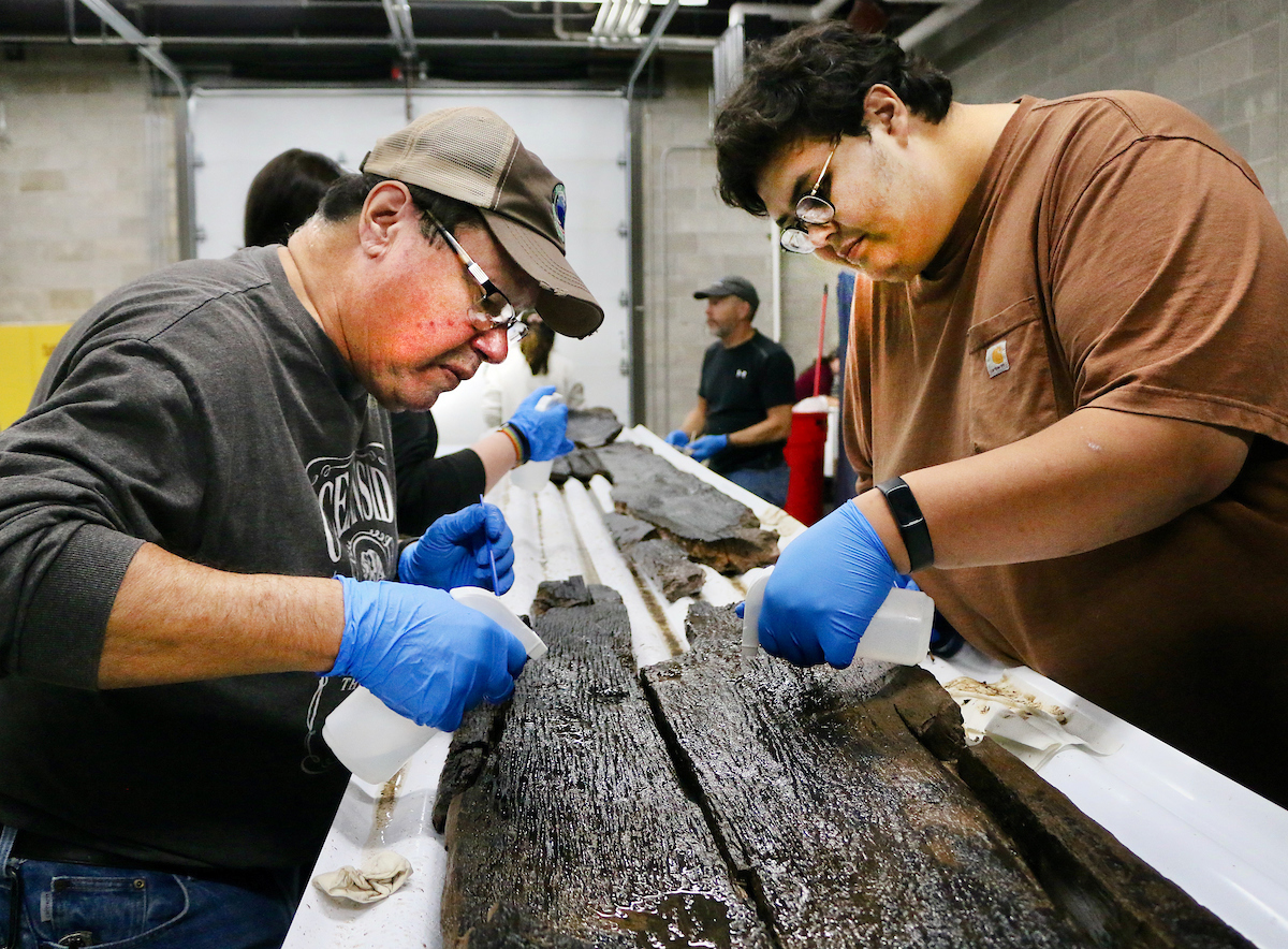 Experts work together to clean a 3,000-year-old dugout canoe recovered from Lake Mendota in 2022