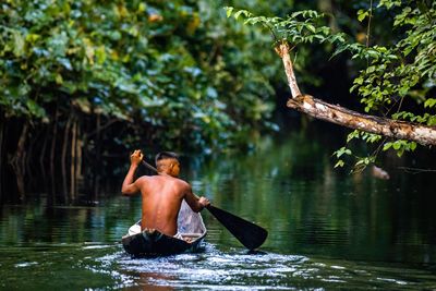 Native man sailing in AMazon river rainforest in handmade boat