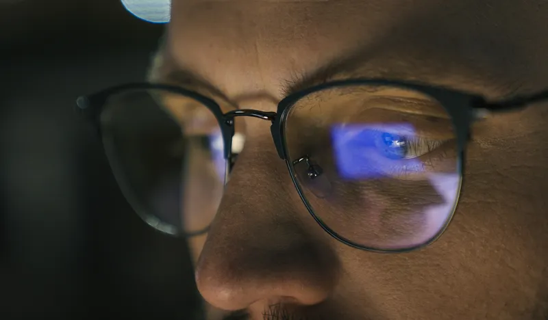 Close up of a man's eyes in glasses looking at a screen, symbolizing concentration and attention.
