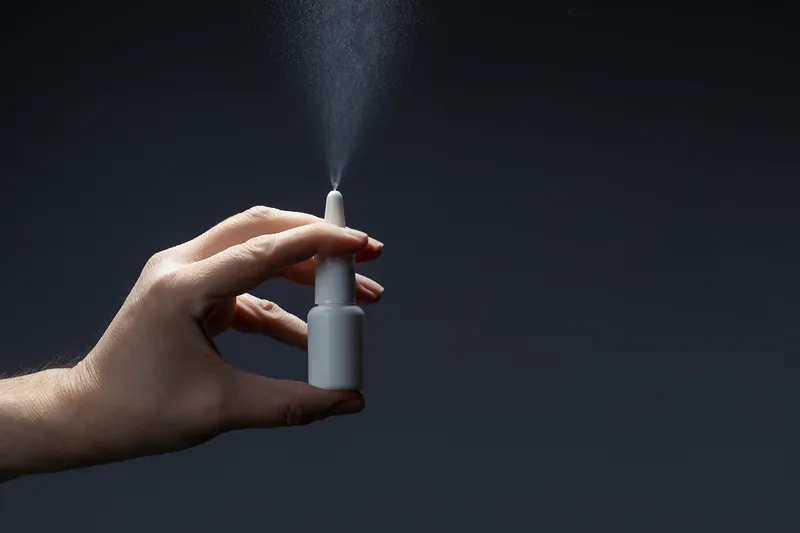 close up of a hand holding a nasal spray bottle
