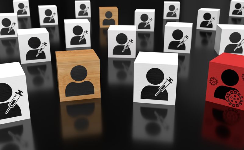 concept of herd immunity - wooden blocks arranged with white ones showing a figure with a syringe, a red one showing a figure with viruses, and plain wooden ones with just figures on them