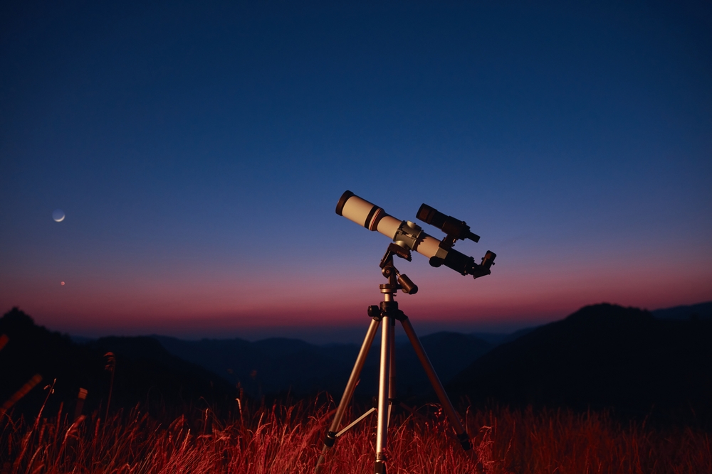 Telescope standing in a field looking up at the sky.