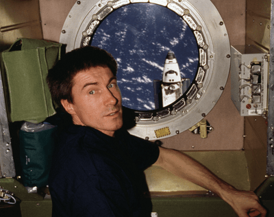 Russian cosmonaut Sergei Krikalev positioned at a port hole on the Zvezda service module of the International Space Station during Expedition 1 as Space Shuttle Atlantis approaches for a link-up