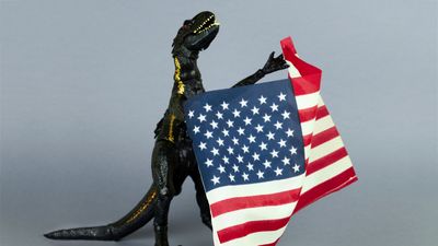 Plastic dinosaur toy holding the flag of the USA