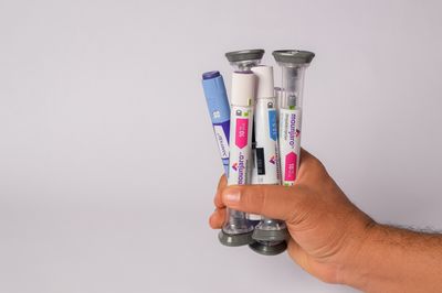hand holding a collection of GLP-1 receptor agonist drug dosing pens