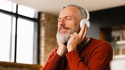 a middle-aged man is wearing headphones and listening to music with a content expression on his face