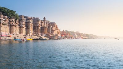 The old castle building beside Ganges river bank in morning wide landscape of famous destination at Varanasi, India.