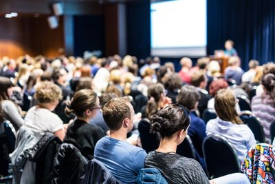View from the rear of an audience in conference hall. 