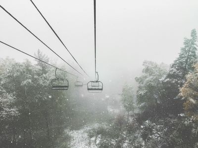 A winter scene from a chair lift surrounded by falling snow and alpine trees