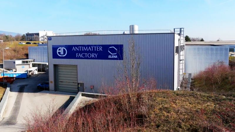 a photo of the antimatter factory from the outside. It is a generic grey warehouse with a big blue sign that says antimatter factory and a large grey shutter.