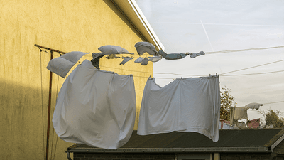 Bed sheets being dried on a washing line outdoors.