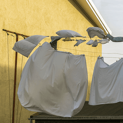 Bed sheets being dried on a washing line outdoors.