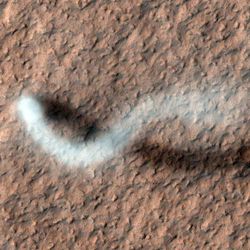 A towering dust devil, casts a serpentine shadow over the Martian surface in this image acquired by the High Resolution Imaging Science Experiment (HiRISE) camera on NASA's Mars Reconnaissance Orbiter.