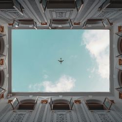 An airplane flies directly over a building's courtyard in Shanghai, China.