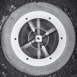 in a metallic donut shaped casing, there is some dark gray loose soil.