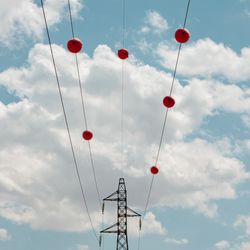 Electric power transmission lines with red marker balls and a background of beautiful cloudy sky.