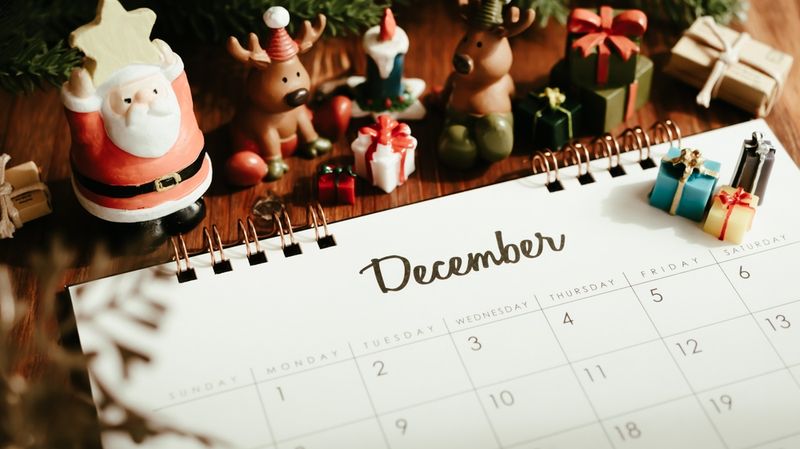 A calendar open on the Dcemeber page with Christmas decorations round it. 