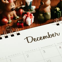 A calendar open on the Dcemeber page with Christmas decorations round it. 