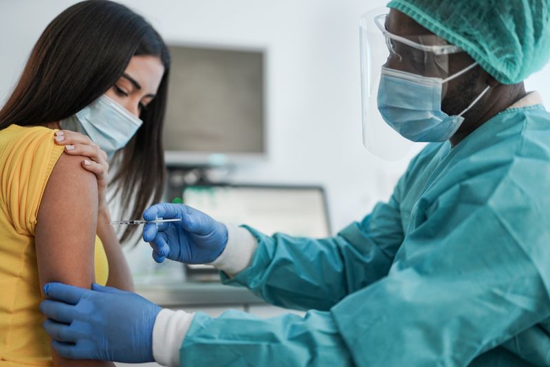 Doctor with syringe injecting a vaccine into someone's arm.