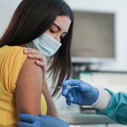 Doctor with syringe injecting a vaccine into someone's arm.