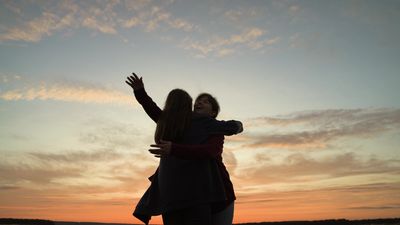 two friends hugging at sunset