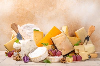 selection of many different cheeses with cheese knives, grapes, walnuts and garnish