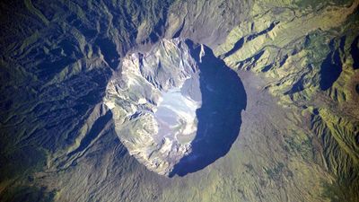 This detailed astronaut photograph depicts the summit caldera of the Tambora volcano. The huge caldera—6 kilometers in diameter and 1,100 meters deep—formed when Tambora’s estimated 4,000-meter-high peak was removed, and the magma chamber below emptied during the 1815 eruption.