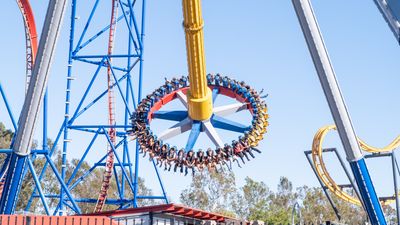 The Wonder Woman spinning ride at six flag. A rotating wheel with people seating at the edge, attached to a central swining pylon.