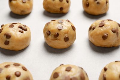 raw chocolate chip cookie dough in balls on a sheet waiting to be baked