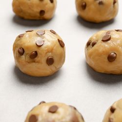 raw chocolate chip cookie dough in balls on a sheet waiting to be baked