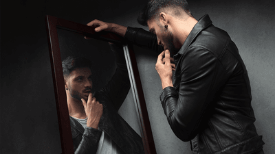 A young man staring at himself in the mirror.