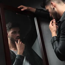 A young man staring at himself in the mirror.
