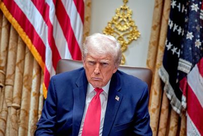 Trump looking at the camera. behind him two US flags