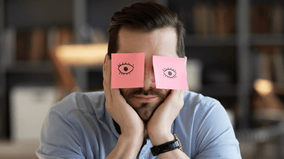 man with head in hands and notes on his eyes, looking unmotivated