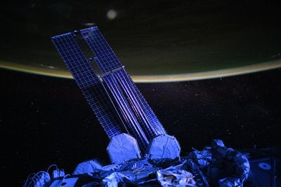 The solar panel are glowing in violet light, with the dark earth and a starry sky behind.
