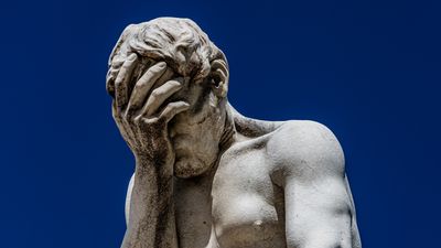 a white marble statue that appears to be faceplaming itself
