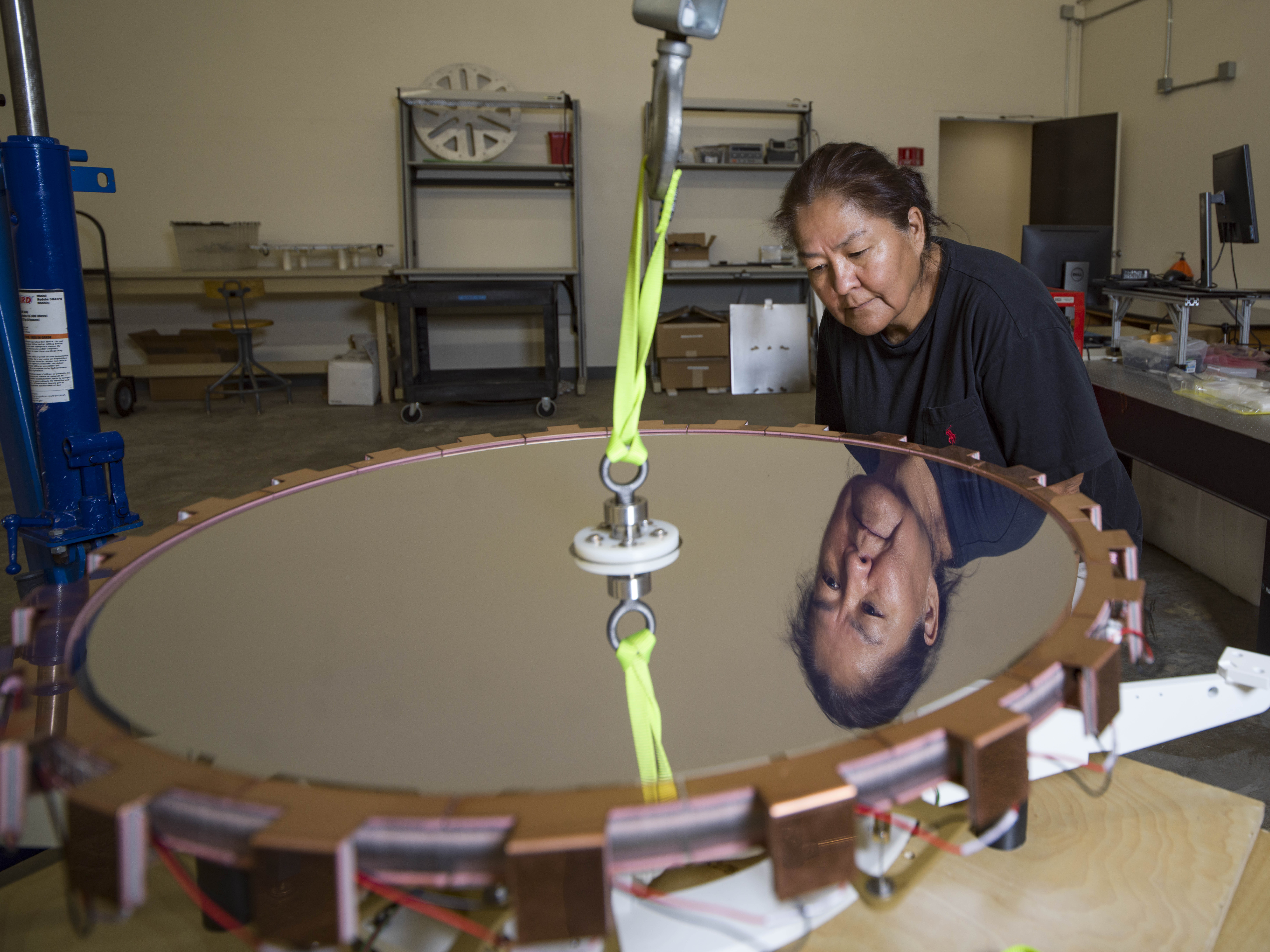A member of the team is looking at the mirror of LFAST her face reflected in it.