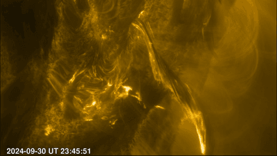 A close-up image of the Sun's surface, with mottled dark black and bright yellow patches. Some yellow arches and streaks of light give an impression of the Sun being very active.
