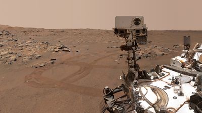 A selfie of perseverance showing its main camera, part of the rover's body, ad the tracks in the sand that the rover left.