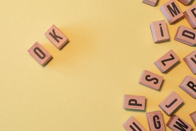 A handful of wooden scrabble letter tiles with thetwo that say "O" and "K" pushed off to the side